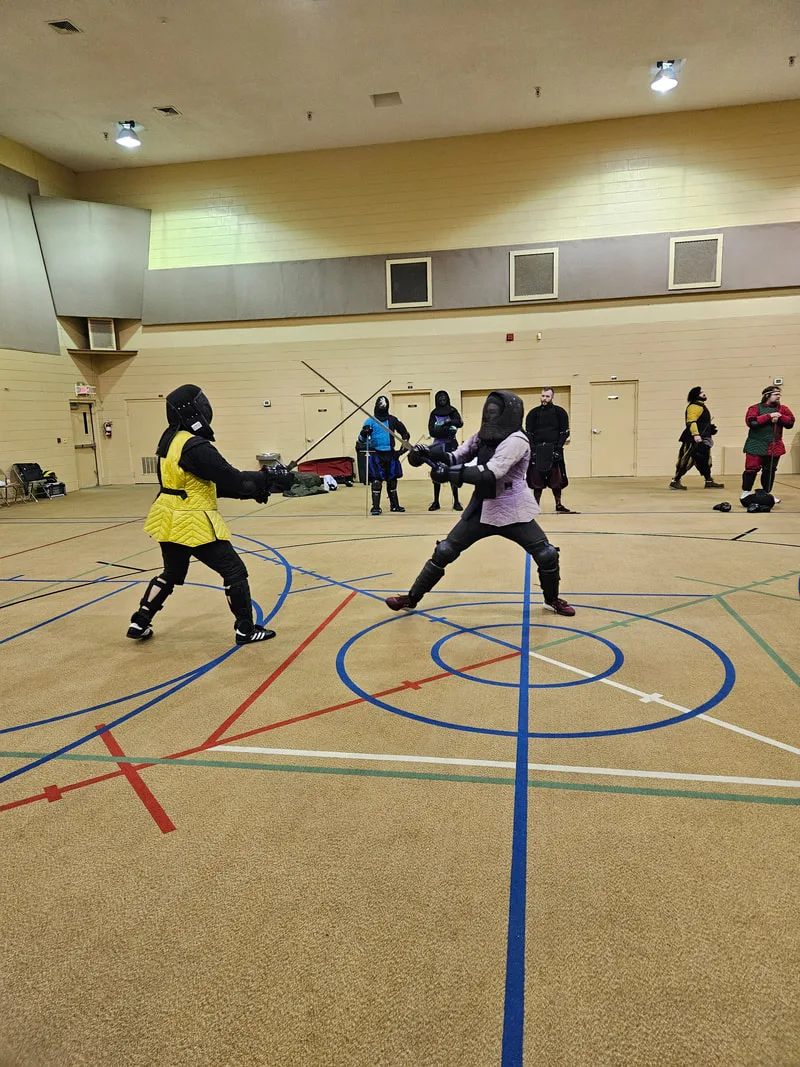 Two adult students engaged in a longsword fight.