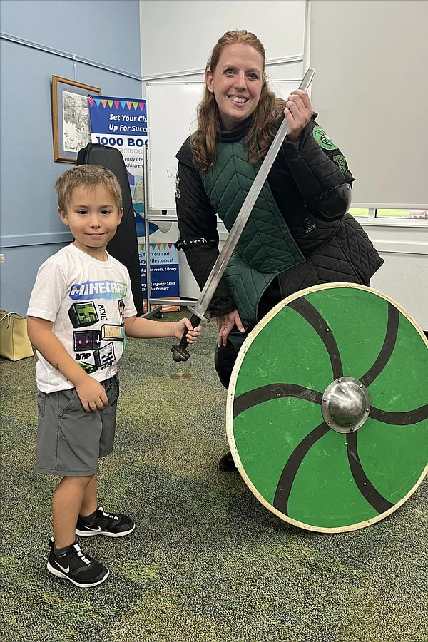 Instructor Amanda at a summer reading program demonstration taking a photo with a child